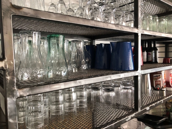 多个玻璃杯在放到货架上的钢板网隔板上。