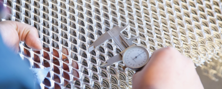 工作人员拿着卡尺正在测量钢板网的长节距。